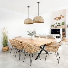 a dining room table and chairs in front of a fire place with potted plants