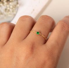 a woman's hand with a green ring on it