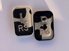 two black and silver metal objects with the letters rrs on them are laying side by side