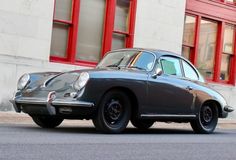 an old porsche sits parked in front of a building