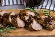 sliced pork with sauce and herbs on a cutting board