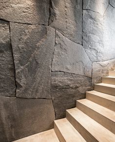 a stone wall next to a set of stairs with white steps leading up the side