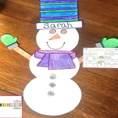 a snowman made out of colored paper on top of a wooden table