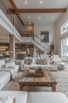 a living room filled with white couches and chairs next to a stair case in front of a window