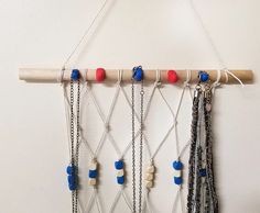 a piece of wood hanging from a wall with beads and chains attached to it,