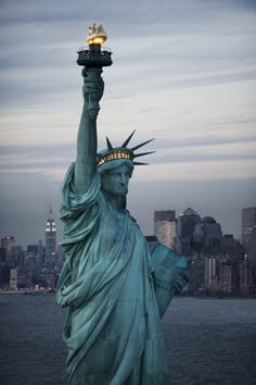 the statue of liberty is holding up a bucket with something in it's hand