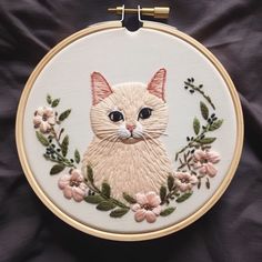 a white cat with blue eyes sitting in a floral frame on a black cloth background