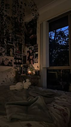 an unmade bed in a dark room with pictures on the wall