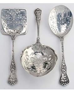 three silver spoons and two serving utensils, each with an ornate design