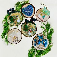 six ornaments are arranged in the shape of wooden slices with words on them and pine needles