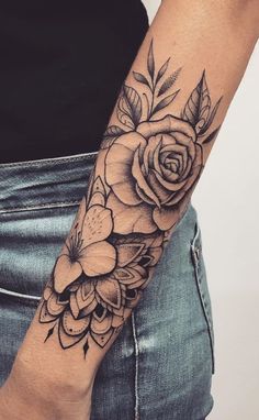 a woman's arm with flowers and leaves on it