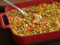 a red casserole dish filled with corn and vegetables