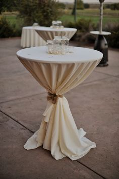 the table is set up with white linens and glassware on it for guests to enjoy