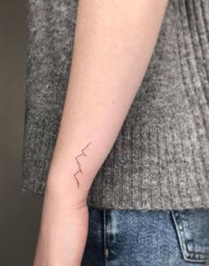 a woman's arm with a small lightning tattoo on the left side of her arm