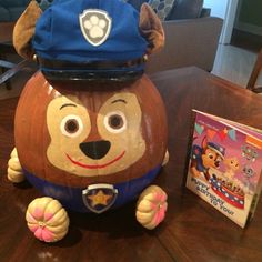 a pumpkin shaped like a police dog with a hat on it's head next to a book