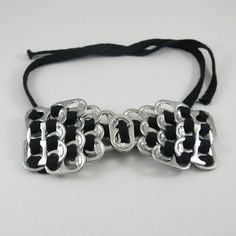 a black and silver bracelet on a white surface with a knot at the end that is attached to it