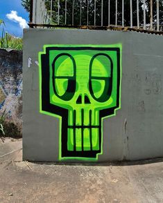 a green skull painted on the side of a cement wall