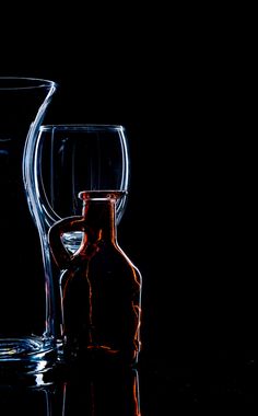 two empty wine glasses and a bottle on a table in front of a black background