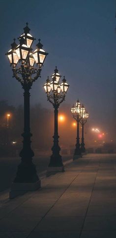 some street lights are lit up on a foggy night