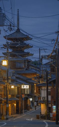 an empty street with many buildings and power lines above it at night in the city