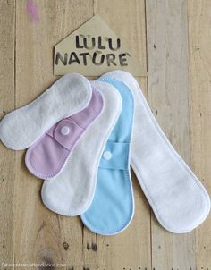 three bibs laying on top of a wooden floor next to a sign that says lulu nature