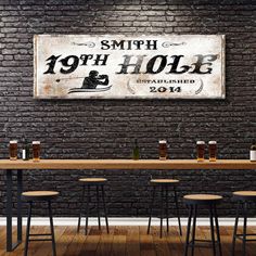 a wooden table with four stools in front of a brick wall that says, 19th hole