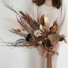 a woman holding a bouquet of dried flowers