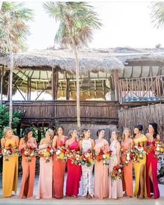 a group of women standing next to each other in front of a hut with thatched roof