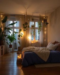 a bedroom with plants and candles on the windowsills, along with a bed