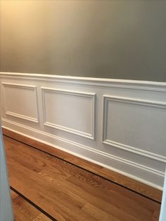 an empty room with hard wood floors and white paneling on the wall above it