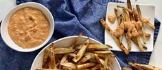 french fries with dipping sauce in bowls on a blue towel next to two white plates