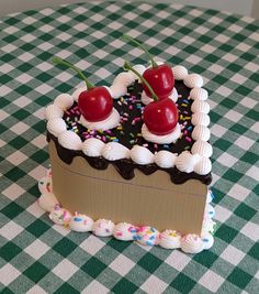 a piece of cake with cherries and sprinkles sitting on a checkered tablecloth