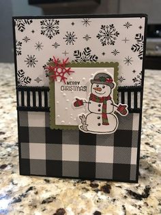 a christmas card with a snowman on the front and black and white checkered background