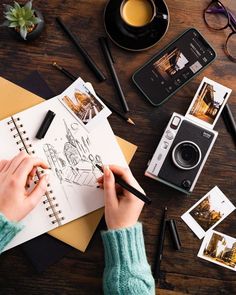 a person is drawing pictures on a table with coffee and other items around them, including an old camera