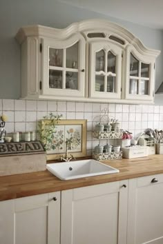 a kitchen with white cabinets and wooden counter tops