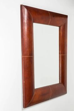 a brown leather framed mirror hanging on the wall