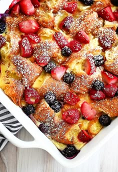 a casserole dish with strawberries and blueberries in it on a table