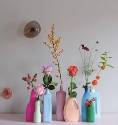 several vases with flowers in them sitting on a table next to a light bulb