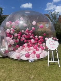 an inflatable bubble ball with pink and white balloons on the ground next to a sign