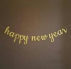 a happy new year banner hanging from a string on a wall with the words happy new year