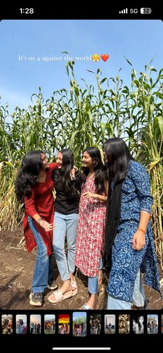 three women standing in front of a cornfield with one woman pointing at the sky