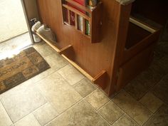 a book shelf sitting on the side of a kitchen floor next to a door way