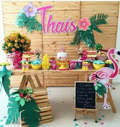 a tropical themed dessert table with pink flamingos and palm leaves on it, including a sign that says thas