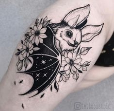 a black and white tattoo with flowers on the thigh, an animal's head is shown