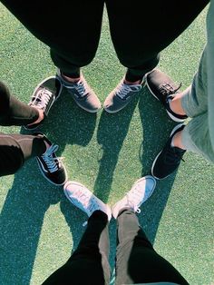 four people are standing in a circle on the ground with their feet up and one is wearing sneakers