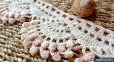 a close up of a crocheted blanket with a snail on the ground next to it