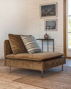 a brown couch sitting on top of a hard wood floor next to a white brick wall