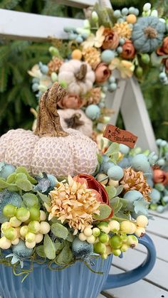 a blue vase filled with lots of different types of flowers next to a white bench