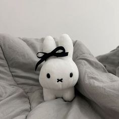 a white stuffed animal with a black bow on it's head sitting on a bed