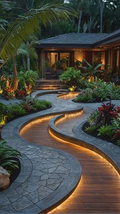 an outdoor walkway lit up at night with lights in the middle and plants on either side